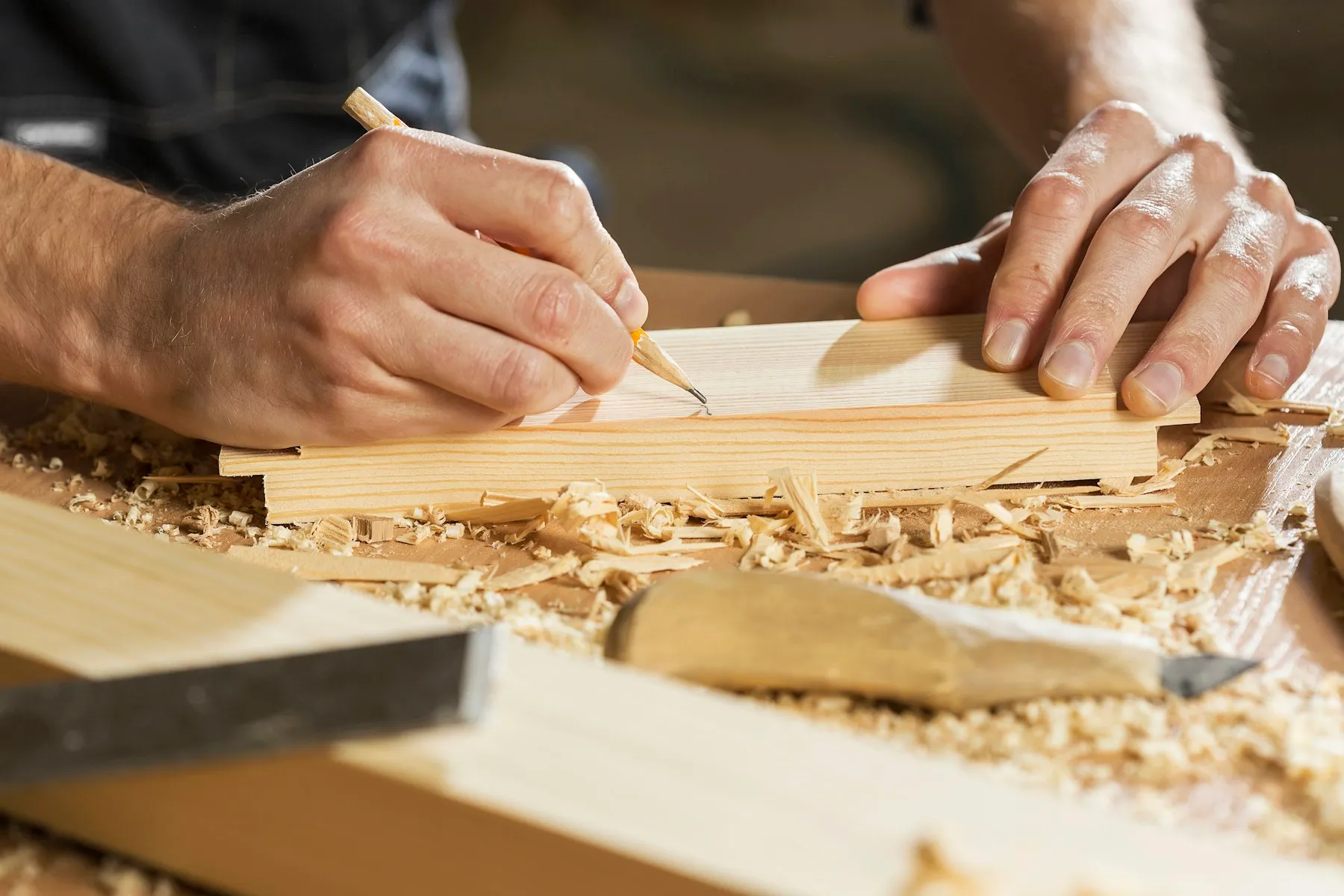 Handwerker zeichnet mit Bleistift eine Linie auf ein Holzbrett